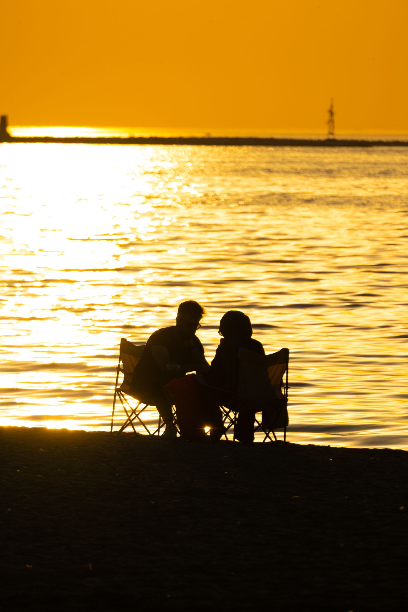 Un couple face à la mer au coucher du soleil.